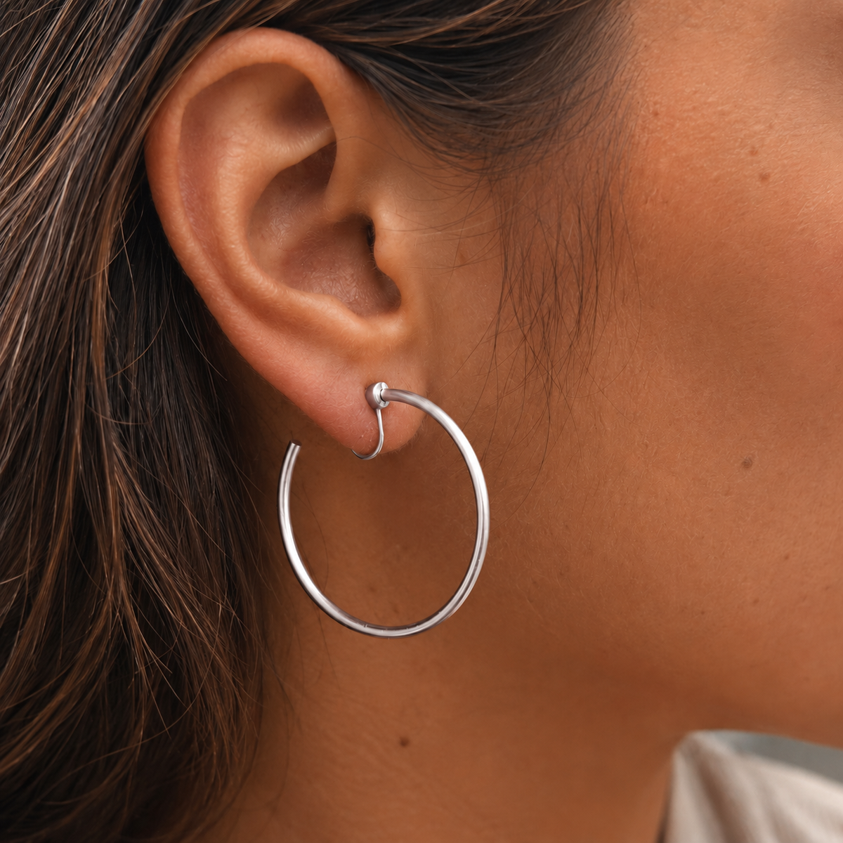 Close-up of SOMIY Large Circle Clip-On Earrings in silver worn on the ear