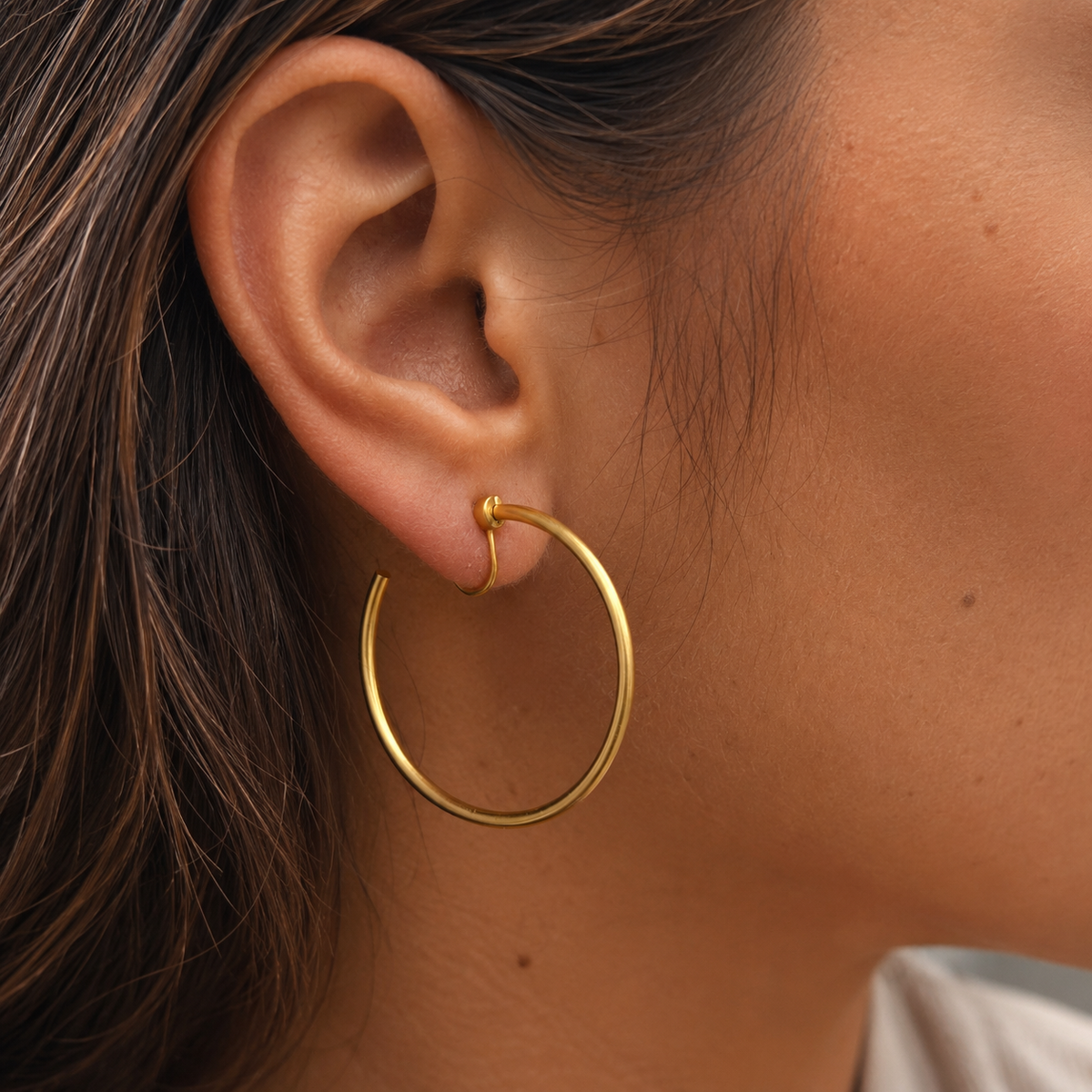 Close-up of SOMIY Large Circle Clip-On Earrings in gold worn on the ear