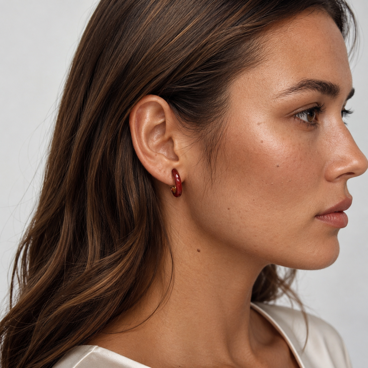 Model wearing SOMIY Burgundy Enamel Clip-On Hoop Earrings in burgundy and gold