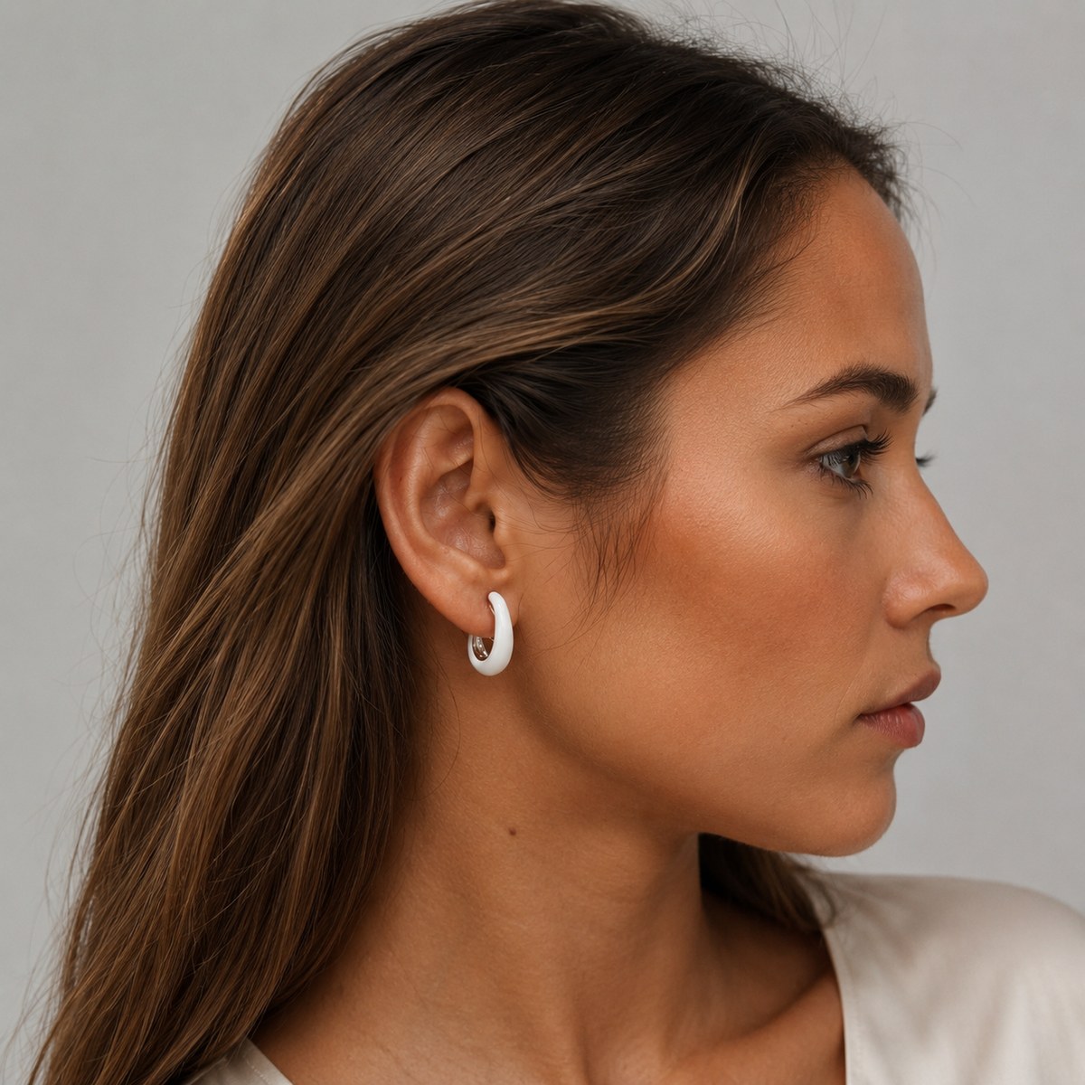 Model wearing SOMIY White Accent Clip-On Hoop Earrings in white and silver, side profile