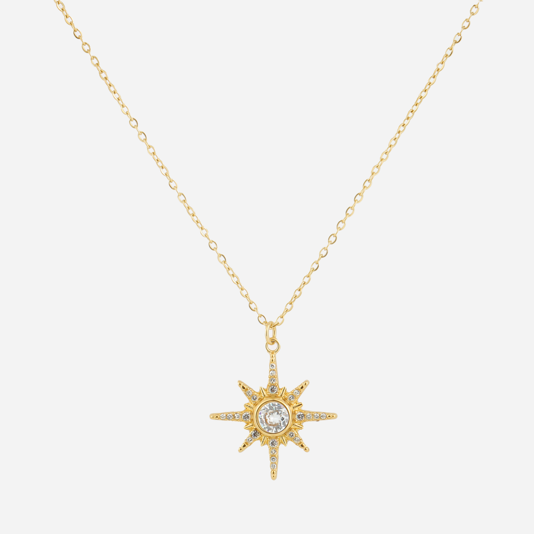 Gold eight-point starburst pendant necklace with a clear center stone