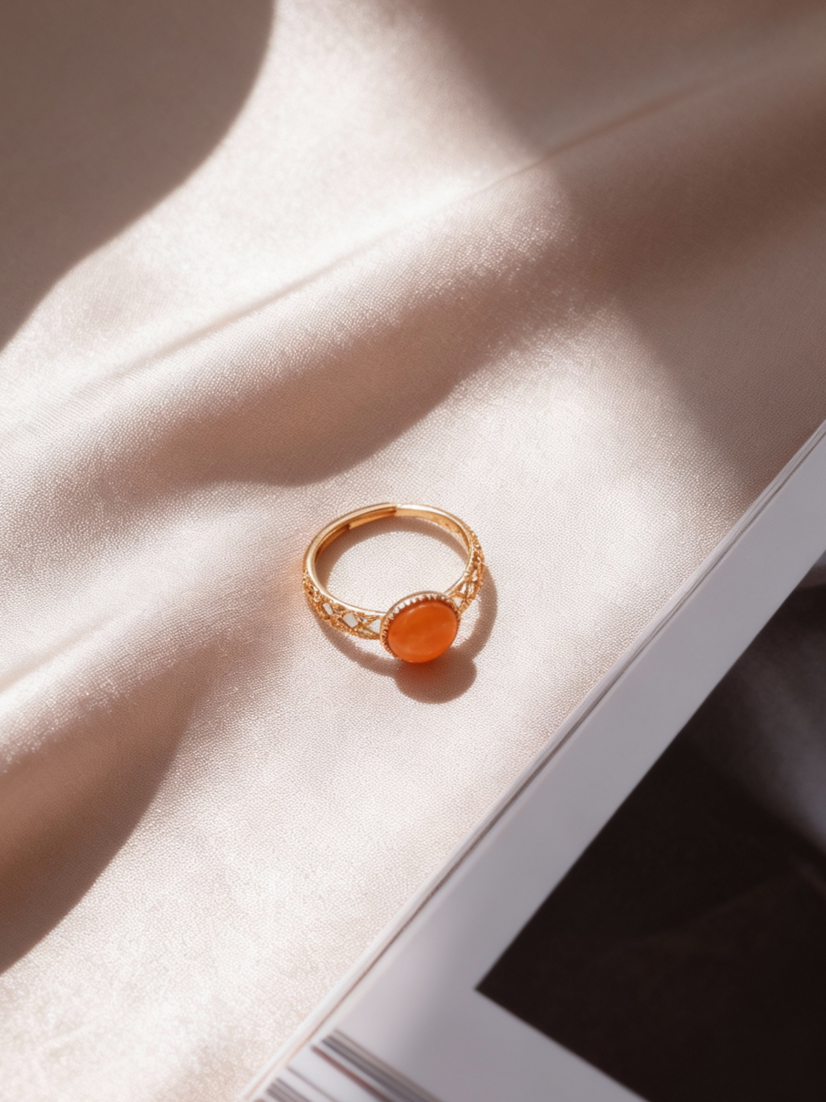 Lattice Filigree amber ring on champagne satin beside an open book