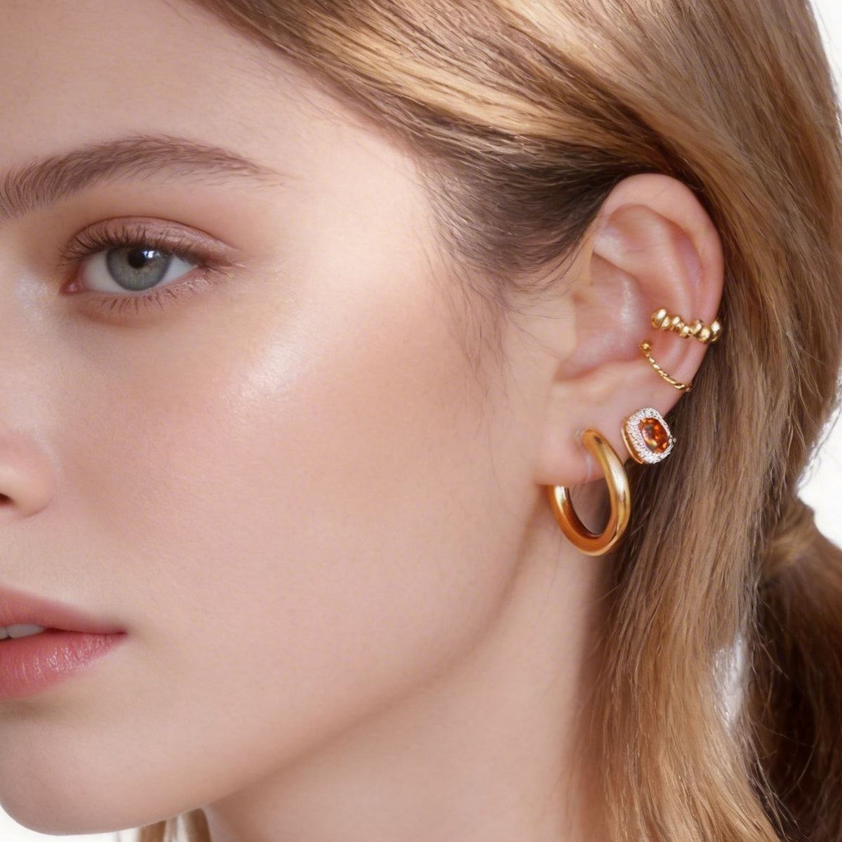 Red halo stud worn with separate gold hoops and ear cuffs