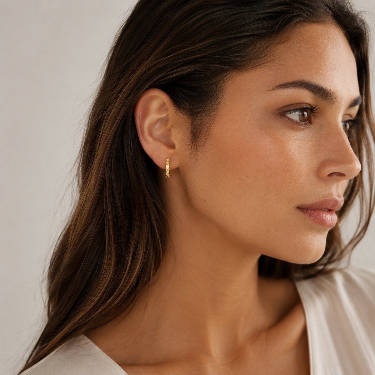 Model wearing SOMIY Möbius Sparkle Clip-On Hoop Earrings in gold