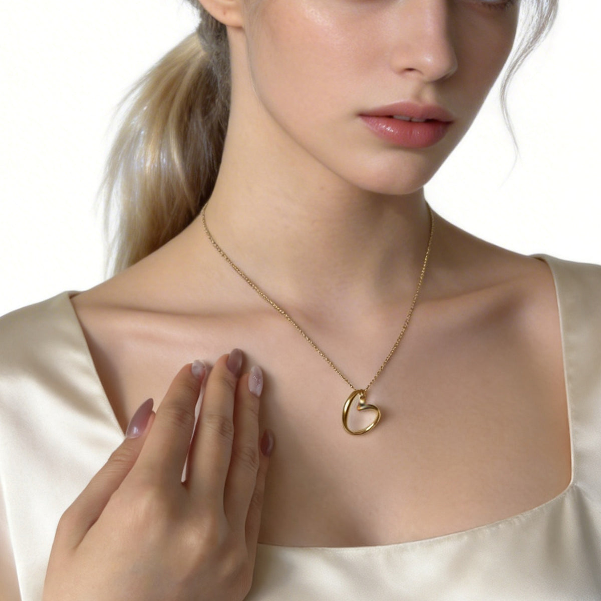 Gold heart-knot necklace worn with a white sleeveless top, front view
