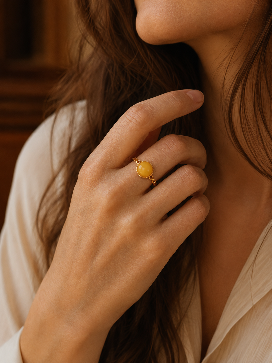 Braided Radiance amber ring worn on a hand in a warm brown interior