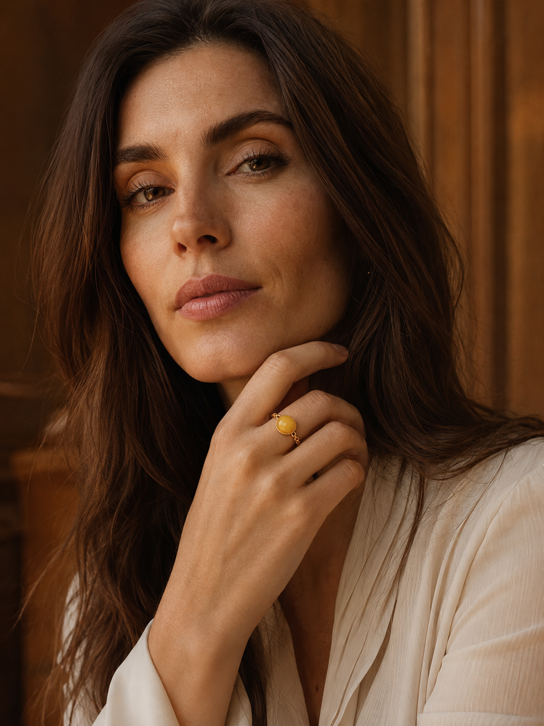 Model wearing the Braided Radiance amber ring with a flowing white blouse