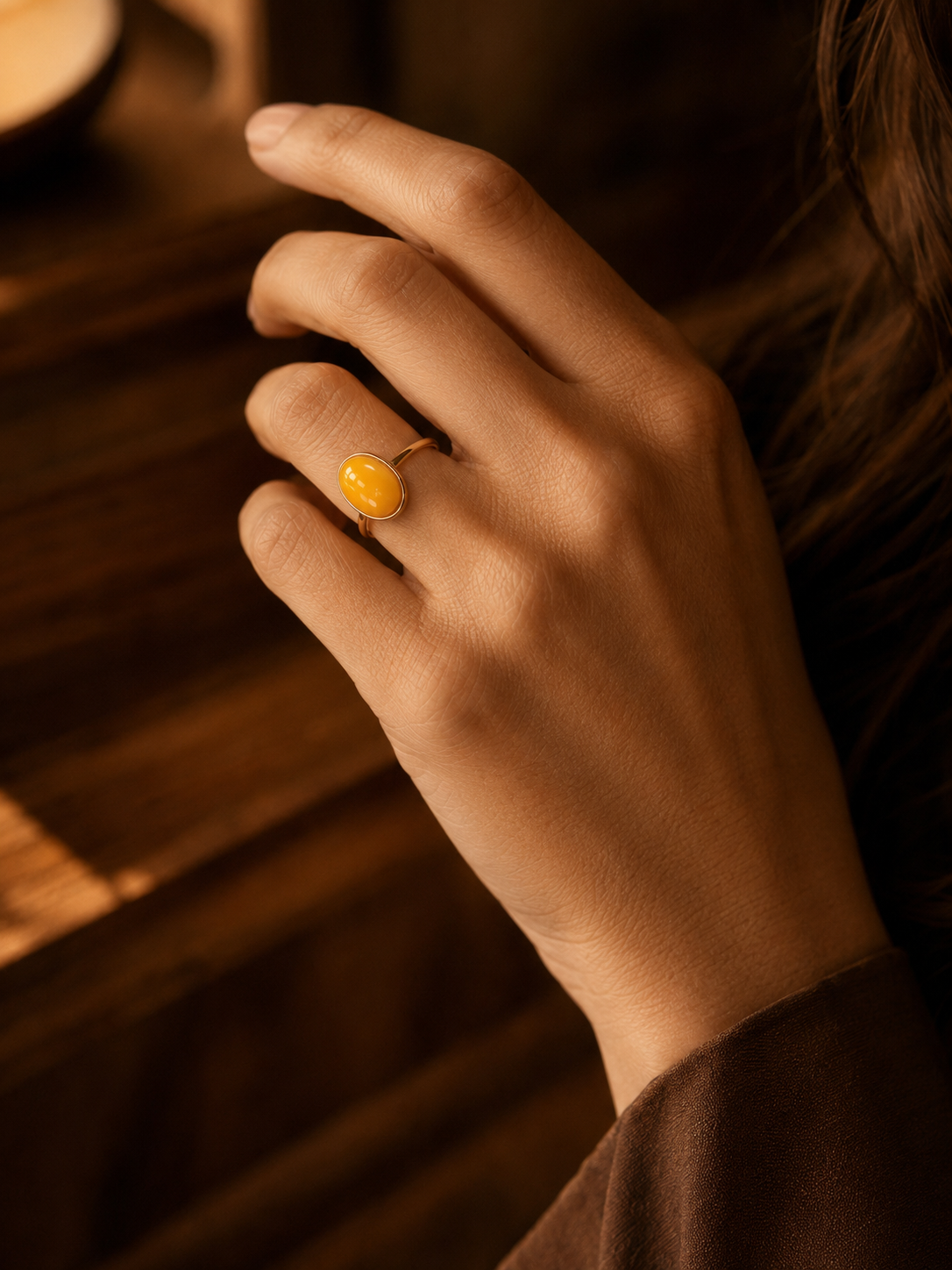 Ethereal Oval amber ring worn on a hand in soft golden window light
