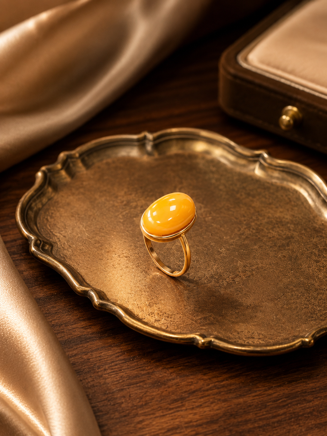 Ethereal Oval amber ring displayed on an antique gold tray with satin
