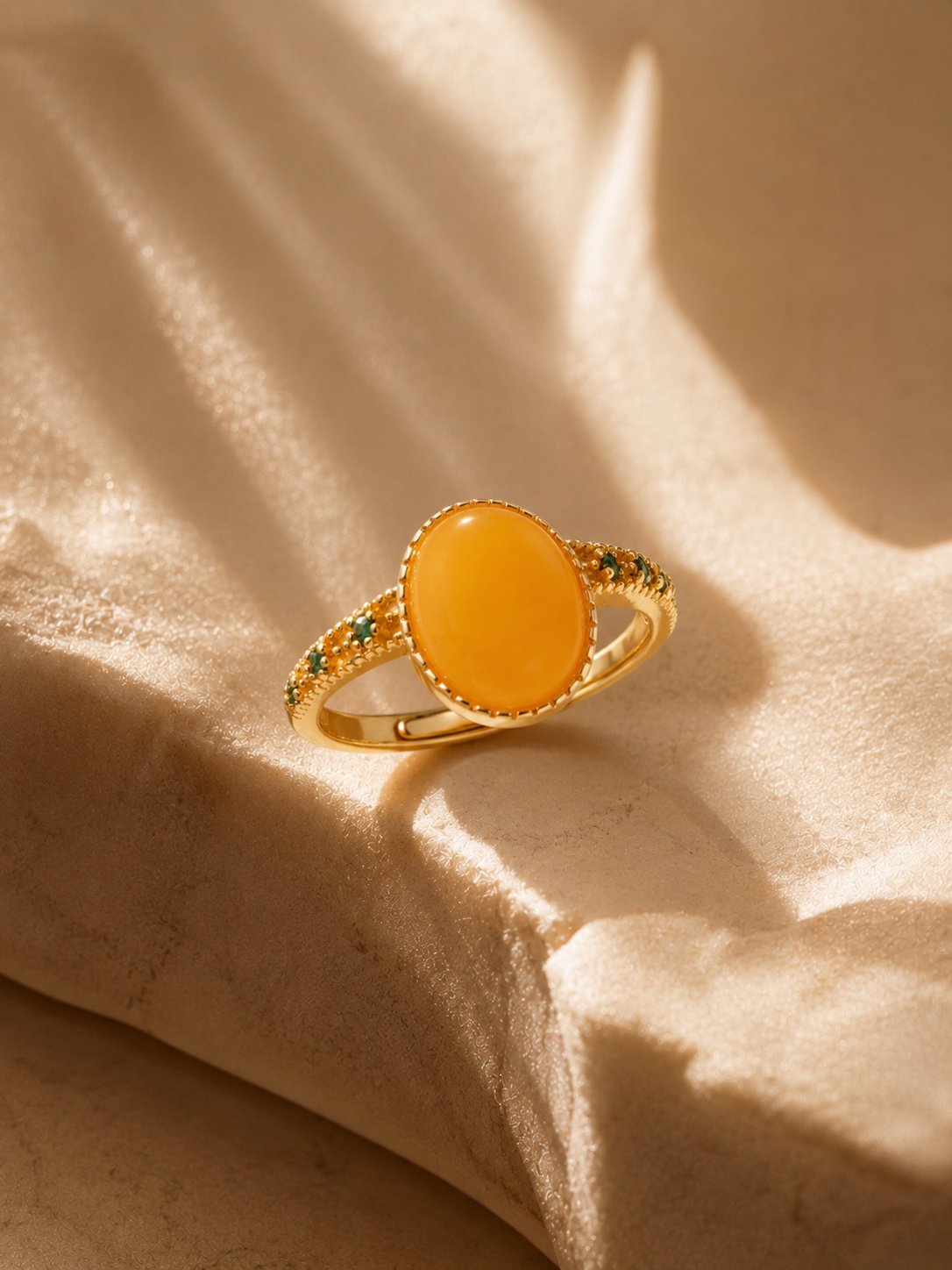 Verdant Vine amber ring on champagne fabric in warm window light