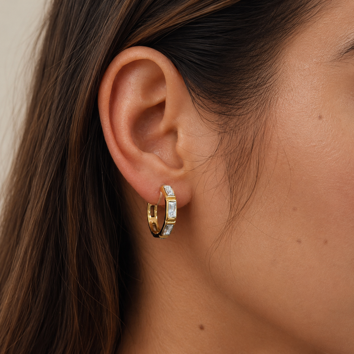 Close-up of SOMIY Bezel Baguette Clip-On Hoop Earrings in gold worn on the ear