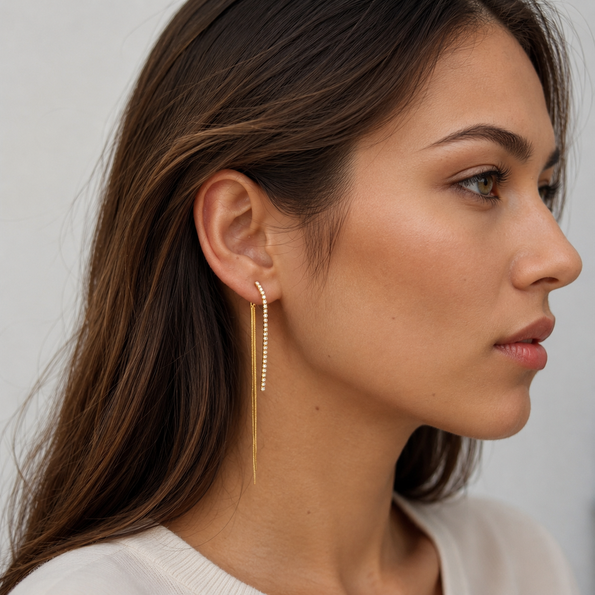 Model wearing a gold crystal chain tassel clip-on drop earring with a white top