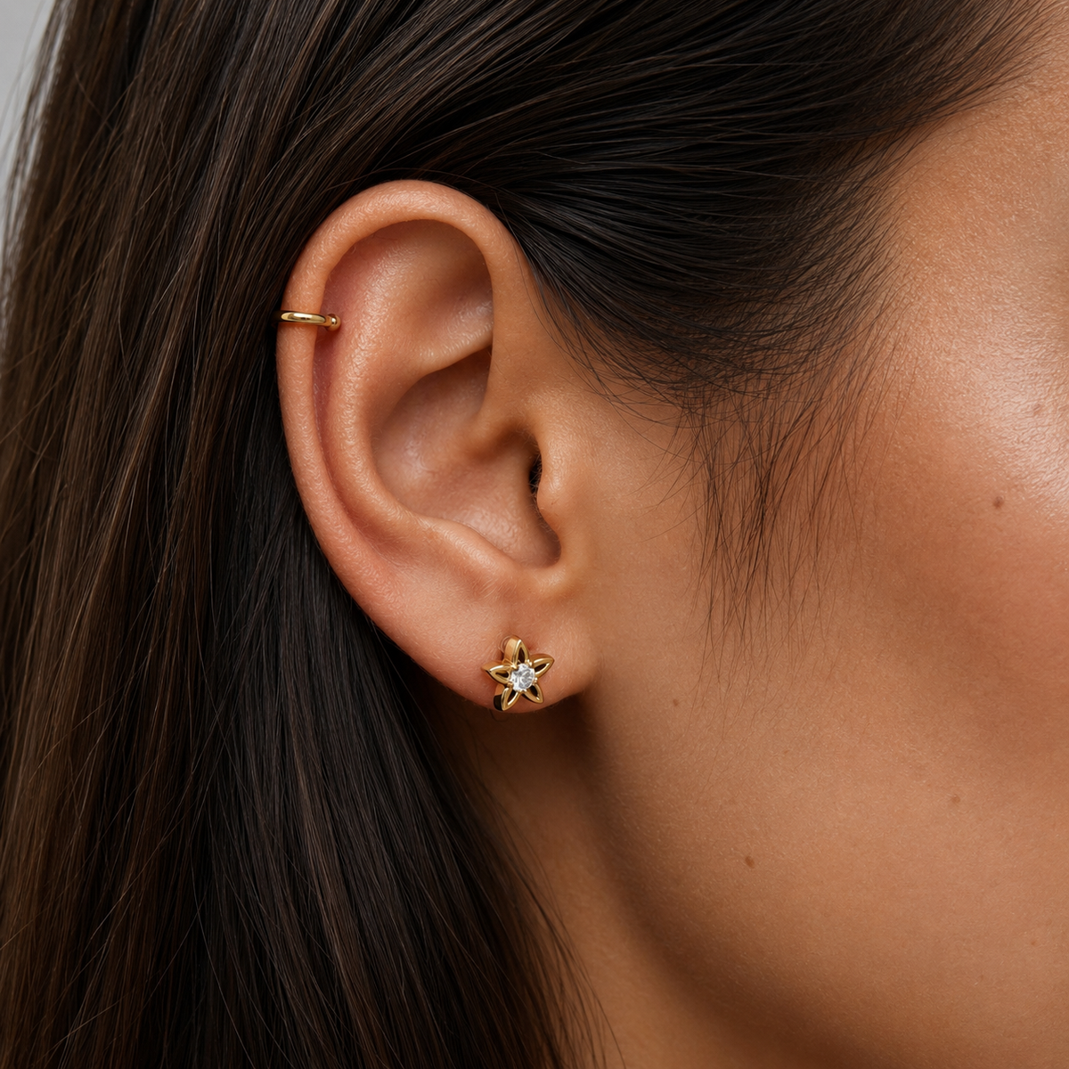 Close-up of SOMIY Mini Star CZ Clip-On Stud Earrings in gold worn with an ear cuff