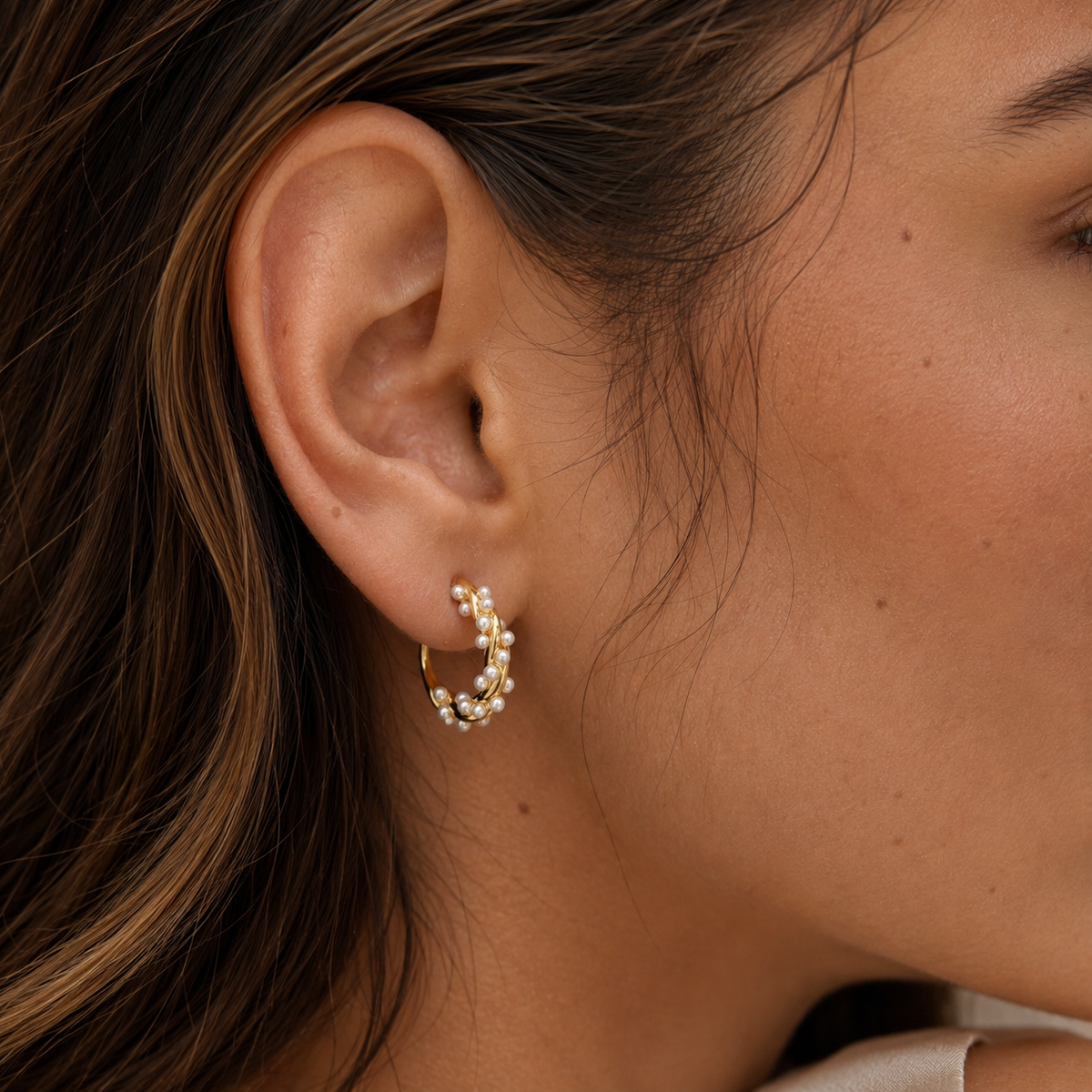 Close-up of SOMIY Mini Pearl Twist Clip-On Hoops in gold worn on the ear