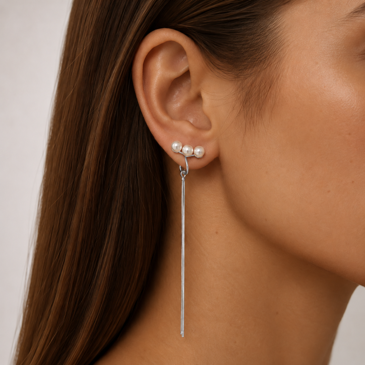 Close-up of SOMIY Triple Pearl Tassel Clip-On Dangle Earrings in silver worn on the ear