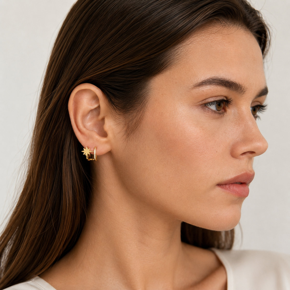 Gold starburst clip-on hoops worn by a model