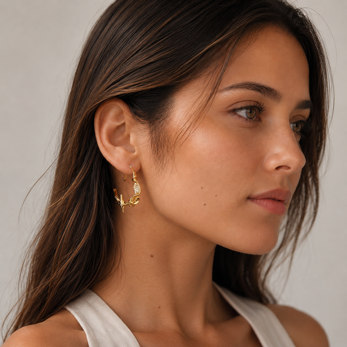 Model wearing a gold Starlight Twist clip-on hoop earring with sparkling zircon accents
