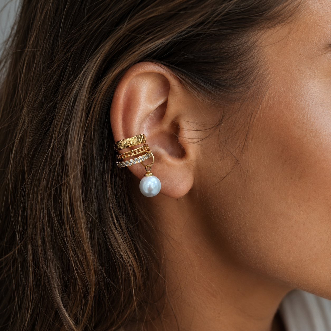 Gold Trio Band Pearl Drop Ear Cuff worn on ear close-up